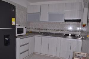 a kitchen with white cabinets and a black refrigerator at Casa para Vacaciones Riohacha in Ríohacha