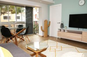 ein Wohnzimmer mit einem TV, einem Tisch und Stühlen in der Unterkunft Sunshine Apartment Fuengirola in Fuengirola