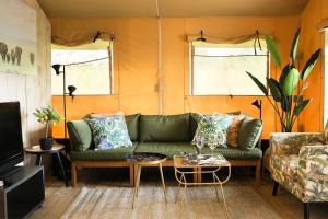 a living room with a green couch and a table at Glamping Safarilodge 'Grutte Fiif' met airco, extra keuken op veranda en privé achtertuin in Grou