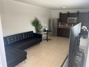a living room with a black couch and a kitchen at Miami haven by airport in Miami
