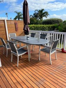 Red Beach Retreat في Red Beach: طاولة وكراسي على سطح مع مظلة