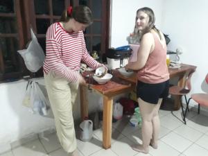 Duas mulheres numa cozinha a preparar comida numa tigela. em Jungle city Hostel em Galle