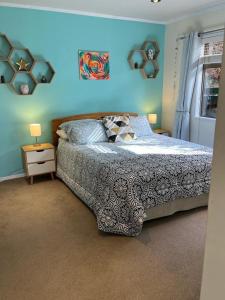 a bedroom with a bed and a blue wall at Red Beach Retreat in Red Beach