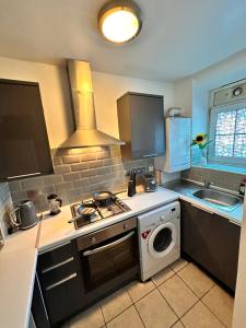 a kitchen with a stove and a washing machine at Perfect family home next to London Bridge in London