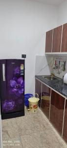 a kitchen with a refrigerator with a purple flower on it at Oman house 2.O in Ernakulam
