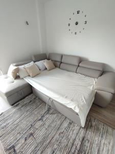 a couch in a living room with a clock on the wall at Sabi Apartment Golem Qerret in Golem