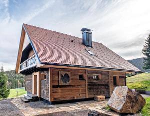 una cabaña de madera con una gran roca delante de ella en Ein JUWEL "zum-Auerhahn", en Modriach