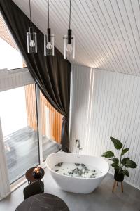 a bathroom with a bath tub in a room with a window at Sniegi design cabin with sauna in Madona