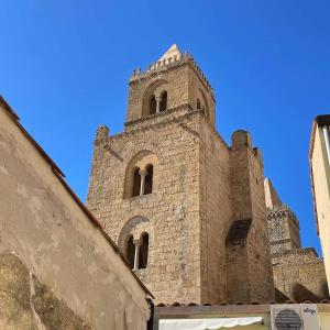 wysoki ceglany budynek z wieżą na górze w obiekcie Rocca&Torre Houses w Cefalù