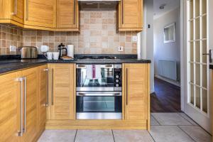 a kitchen with wooden cabinets and a stove top oven at Fair View - Off Street Parking and Garden in Shrewsbury