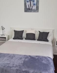 a white bed with black pillows in a room at El Palomar Misiones 6574 in El Palomar