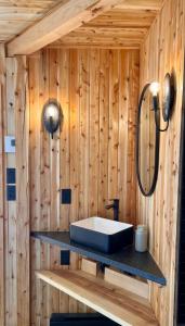 a bathroom with a sink on a wooden wall at mi-clos - luxury pods with private jacuzzis in Orford