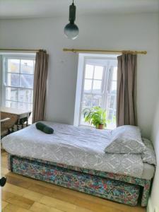 a bed in a room with two windows at Brynawel in Aberystwyth