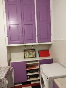 a laundry room with purple cabinets and a washing machine at Комната pilika 4room with shared bath in Athens
