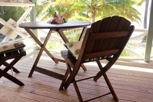 a wooden table and a chair sitting next to a table at Paparei Beachfront Bungalows, Aitutaki in Arutanga