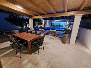 een patio met een houten tafel en stoelen bij VILLA ENJOY LUX private heated pool in Split in Split