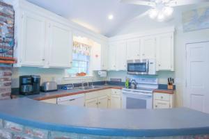 a kitchen with white cabinets and a blue counter top at Shell Station House in Folly Beach