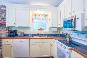 a kitchen with white cabinets and a sink and a window at Shell Station House in Folly Beach +42 photos