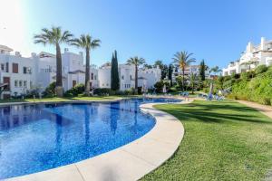 een zwembad in een resort met palmbomen en gebouwen bij Los Monteros Palm Beach - ground floor apartment in Marbella