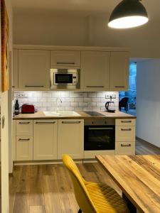 a kitchen with white cabinets and a wooden table at Corner Apartman in Kőszeg