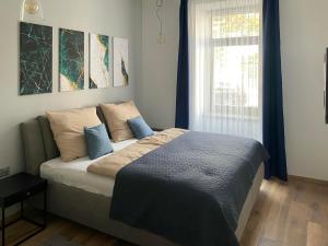 a bedroom with a bed with blue pillows and a window at Corner Apartman in Kőszeg