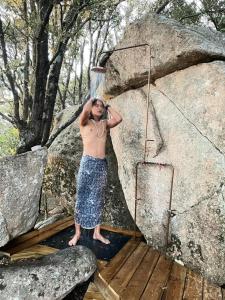 un hombre sin camisa parado junto a una gran roca en CORSICA NATURA #1, en Coti-Chiavari