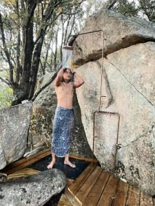 un uomo a torso nudo in piedi accanto a una grande roccia di CORSICA NATURA #1 a Coti-Chiavari