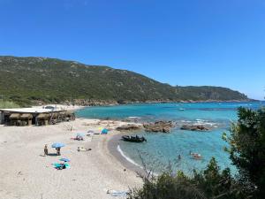 a beach with people and umbrellas in the water at CORSICA NATURA #1 in Coti-Chiavari