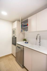 帕拉莫斯的住宿－Gran piso en Puerto deportivo Marina Palamós IDEAL FAMILIAS，厨房配有白色橱柜和不锈钢用具