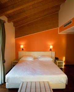 a bedroom with a large bed with an orange wall at Hotel Ristorante Vecchia Riva in Varese