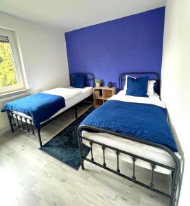 a bedroom with two beds and a blue wall at AMS Apartments The Royal Blue in Spaichingen
