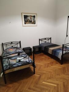 two beds sitting in a room with wooden floors at Комната pilika 4room with shared bath in Athens