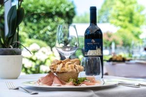 a plate of food on a table with a bottle of wine at Hotel Ristorante Vecchia Riva in Varese