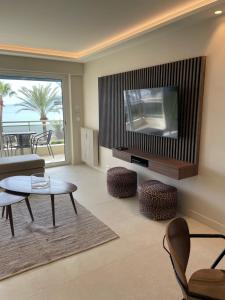 - un salon avec une télévision, une table et des chaises dans l'établissement Appartement Rottaro luxueux 2 ch 2 sdb face à la mer, à Cannes