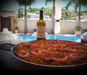 Una botella de vino sentada junto a una pizza y una botella de comida. en Casa Pozuelo, en Taramay