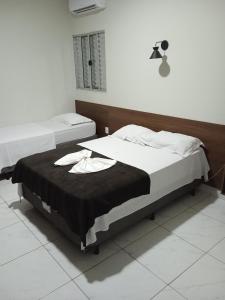 a bedroom with two beds with a black blanket at HOTEL IMPERIO in Aparecida do Taboado