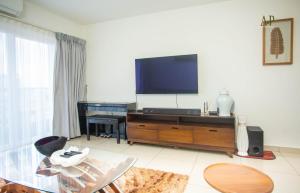 uma sala de estar com uma televisão de ecrã plano e uma mesa em Adrich Properties Gallery em Acra