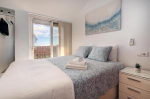 Schlafzimmer mit einem weißen Bett und einem Fenster in der Unterkunft Top Floor Fuengirola Park Apartment with Parking in Fuengirola
