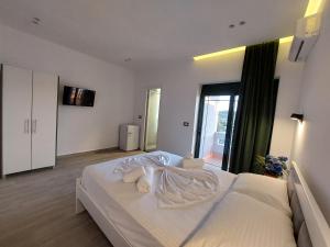 a bedroom with a large white bed with towels on it at Villa Vento in Ksamil