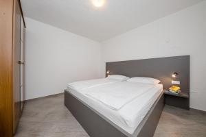 1 dormitorio con 1 cama grande con sábanas blancas en Apartments Kos, en Supetarska Draga