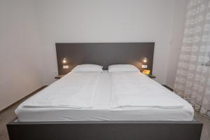 1 cama blanca grande en una habitación con 2 lámparas en Apartments Kos, en Supetarska Draga