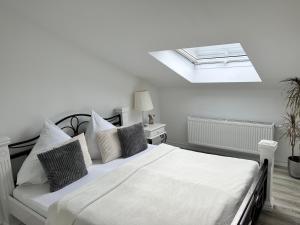 a white bedroom with a bed and a skylight at Prime Host apartments in Karlsruhe