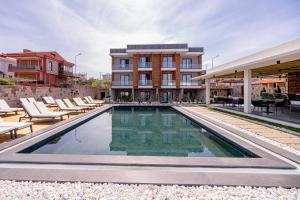 a swimming pool with chairs and a building at Leone Cunda Edition Otel in Ayvalık