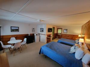1 dormitorio con 1 cama azul, mesa y sillas en Yardarm Motel, en Searsport