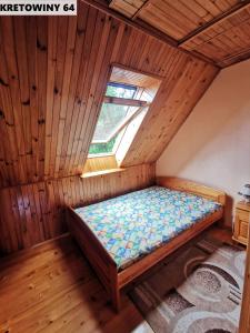 a small bed in a room with a window at Duży Domek Nad Jeziorem - Kretowiny 64 in Kretowiny