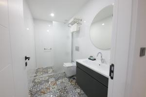 Baño blanco con lavabo y espejo en White House Cappadocia, en Nevşehir