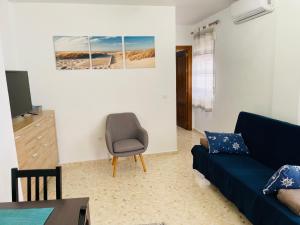 ein Wohnzimmer mit einem blauen Sofa und einem Stuhl in der Unterkunft Apartamento Conil Playa & Centro, perfecto descanso, con Aire Acond y WIFI in Conil de la Frontera