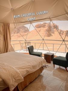 a bed and two chairs in a tent with a view at RUM CHEERFUL lUXURY CAMP in Wadi Rum
