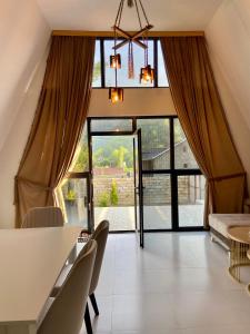 a living room with a table and chairs and a large window at A Frame Lerik in Lerik