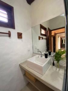 ein Badezimmer mit einem weißen Waschbecken und einem Spiegel in der Unterkunft Pontal da Enseada in Pôrto de Pedras